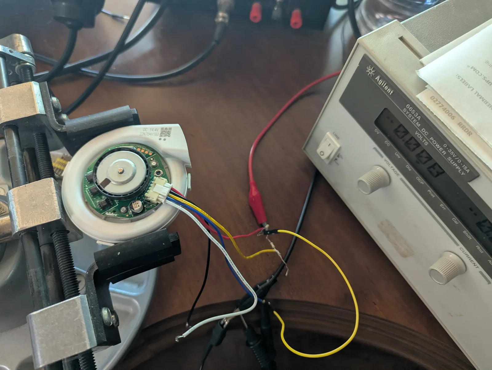 Nidec 22N704V160 blower clamped in a vise, wired to a bench supply