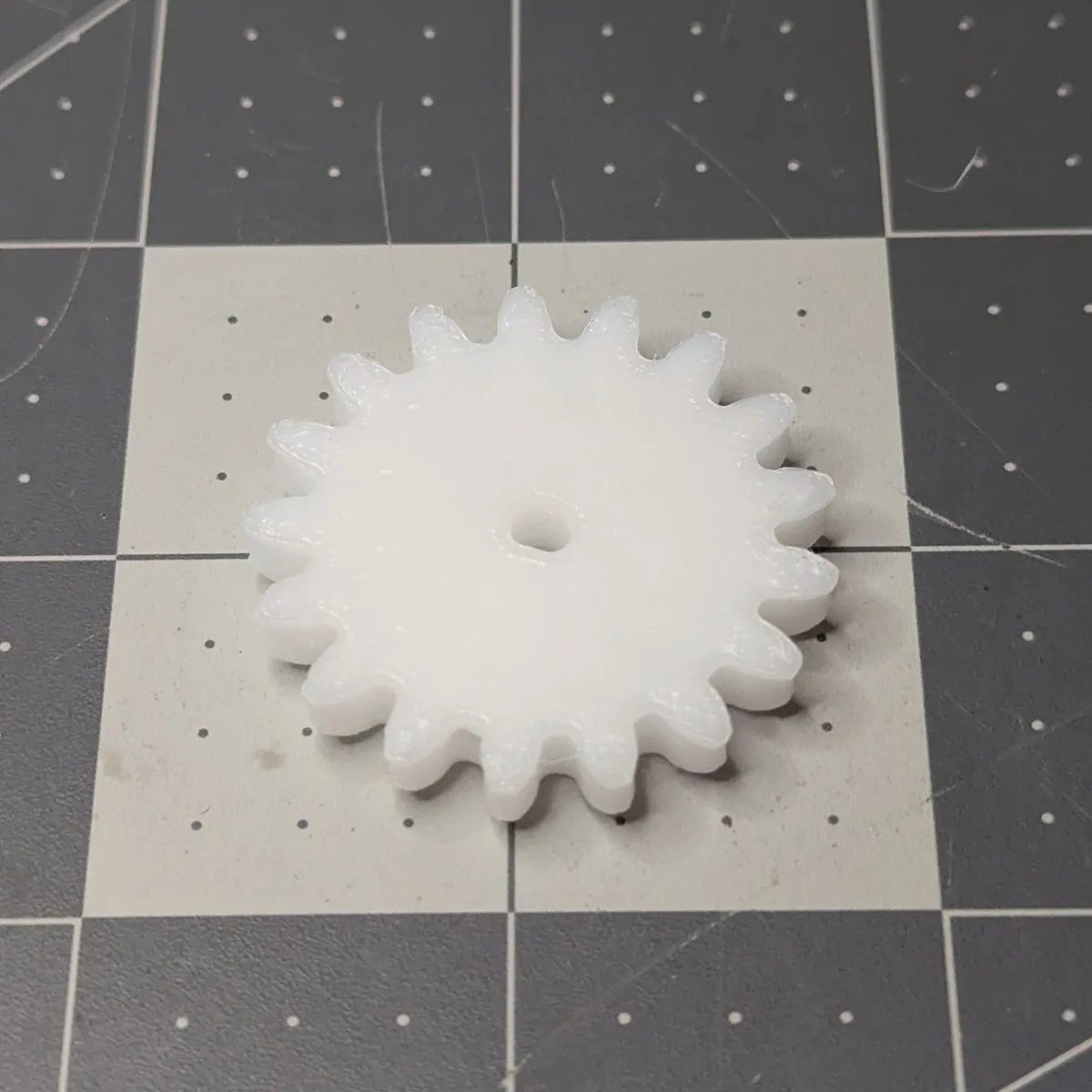 A white 17-tooth spur gear 3D printed in POM (Delrin), top side