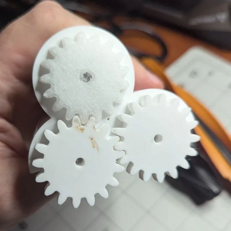 Three meshed 3D-printed spur gears of the OOMWOO main brush gearbox, one printed in POM and two in PETG